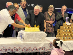 Representative of the Fatima House partnership cutting the celebratory cake together.