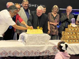 Representative of the Fatima House partnership cutting the  celebratory cake together.