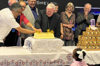 Representative of the Fatima House partnership cutting the celebratory cake together.