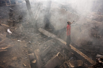 Palestinian man searches through wreckage of his home after an Israeli strike in Gaza. 24 July.