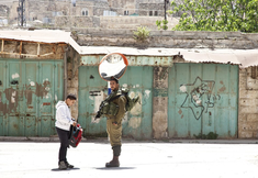 Israeli solider searches boy's school bag in Hebron. The boy is a member of one of the few remaining Palestinian families to live in the old centre of Hebron. Palestinians who do not live there are not allowed enter. Photo: Alan Whelan.