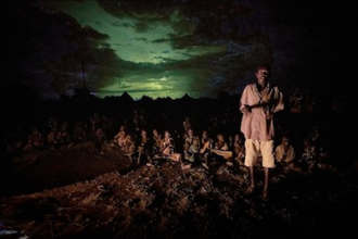 As lightning illuminates the sky behind them, a man speaks during a nighttime prayer vigil for peace in Nakubuse, a small village near Kuron in South Sudan. Photo: Paul Jeffrey/WCC