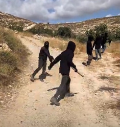 Masked settlers wielding stones and clubs. Photo by Liora Binyamin.
