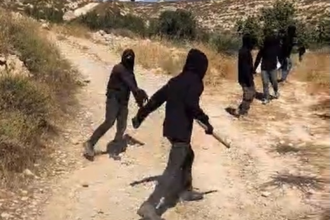 Masked settlers wielding stones and clubs. Photo by Liora Binyamin.